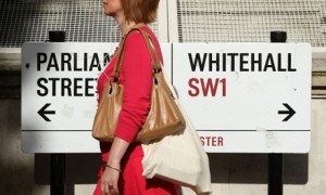 civil_service_woman_walking_past_whitehall_sign-300x180